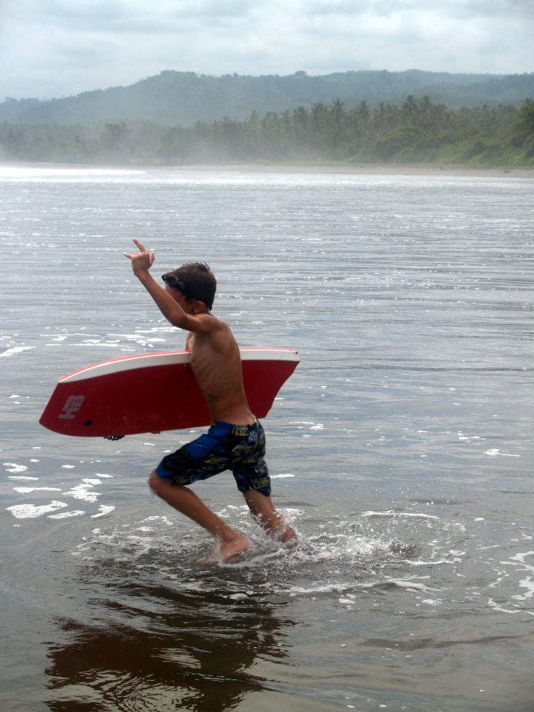 a kid has fun on the beach with a body board