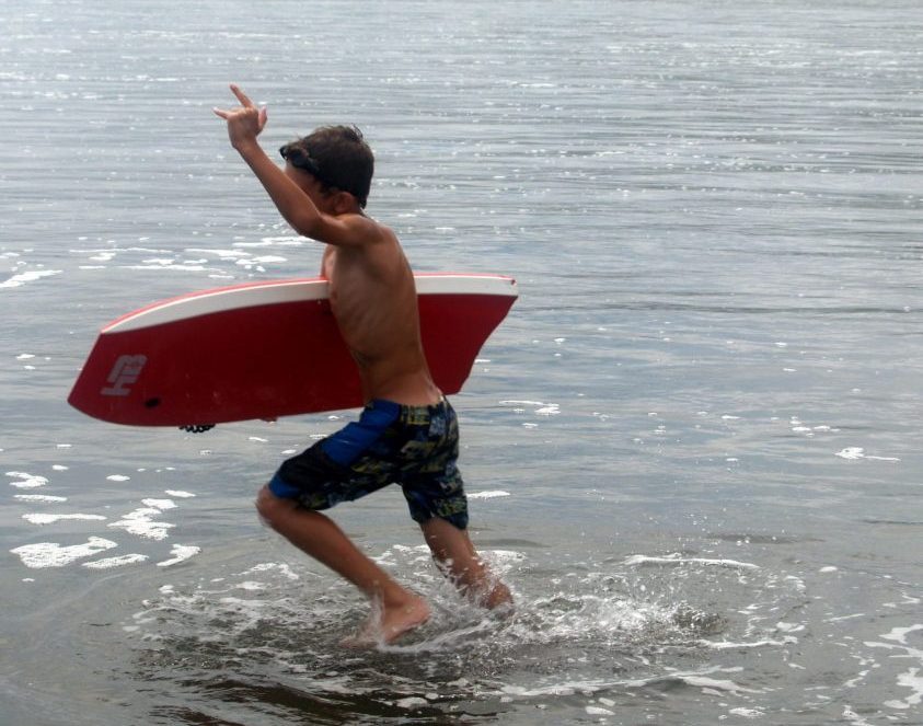 a kid has fun on the beach with a body board