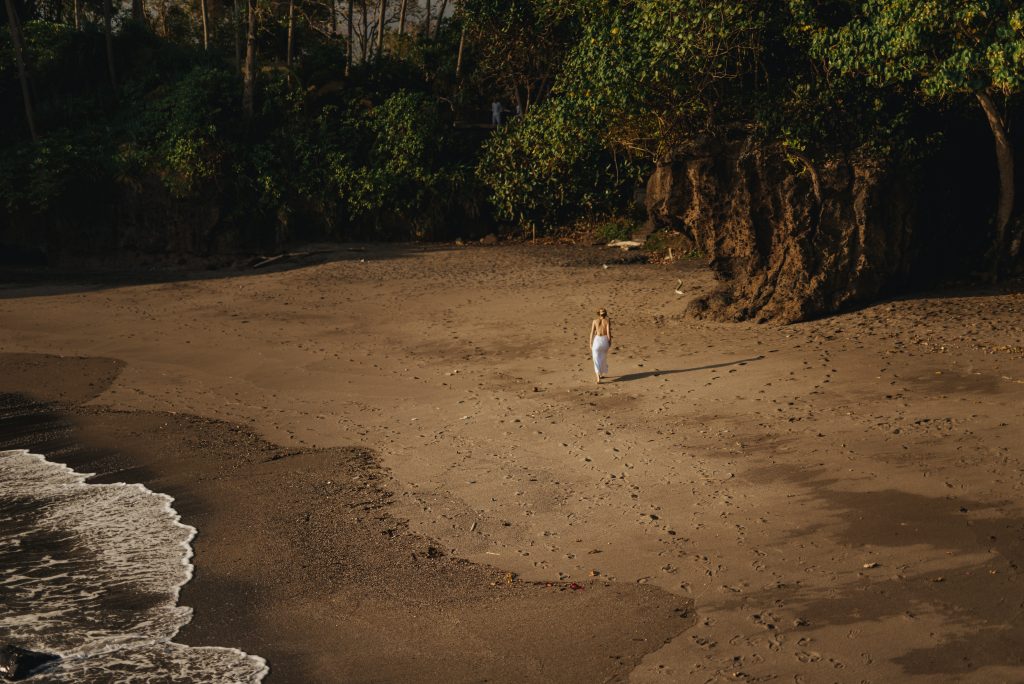 a woman walks alone on a pristine exotic beach