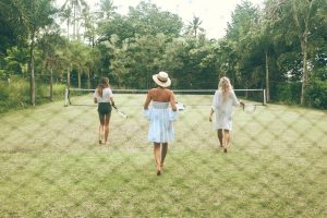 three young women on a tennis court